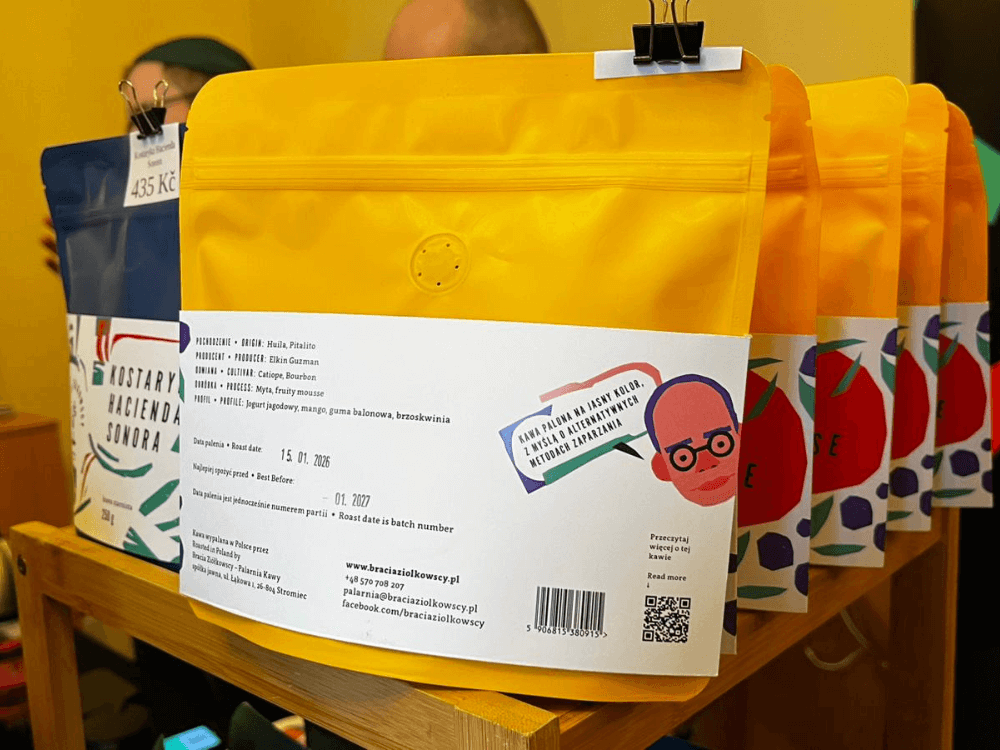 Žlutý kávový pytlíček s etiketou, kde jsou uvedené informace o kávě.